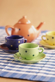 Teapot, cups and saucers on a chequered table cloth Teapot, cups and saucers on a chequered table cloth
