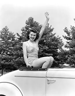 Teenage girl in bathing suit waves from inside convertible car Teenage girl in bathing suit waves from inside convertible car