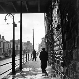 Rail Transportation Collection: Tiger Bay; A man walking under a railway bridge in the dockland area of Cardiff