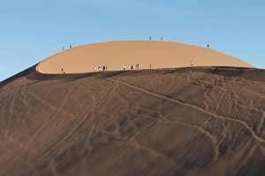 Tourists walking on the top of the famous Dune 45 sand dune. Sossuvlei, Namibia Tourists walking on the top of the famous Dune 45 sand dune. Sossuvlei, Namibia