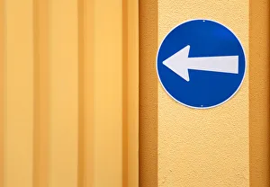 Traffic sign, arrow to the left, on the wall of a building Traffic sign, arrow to the left, on the wall of a building