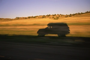 USA, Montana, SUV casting shadow on roadside, sunset (blurred motion) USA, Montana, SUV casting shadow on roadside, sunset (blurred motion)