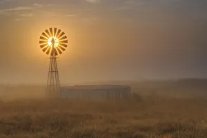 Windmill Backlit at Sunrise in the Mist and Fog of a Cold Winter Morning, Free State Province, South Africa Windmill Backlit at Sunrise in the Mist and Fog of a Cold Winter Morning, Free State Province, South Africa