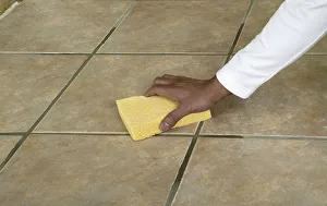 Wiping the surface of a tiled floor with a sponge Wiping the surface of a tiled floor with a sponge