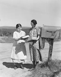 Two women collect mail from country mailbox Two women collect mail from country mailbox