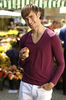 Young happy man holding an apple at a market Young happy man holding an apple at a market