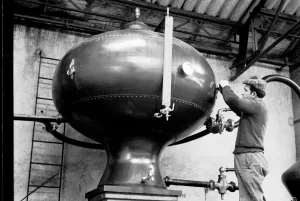 French distillery worker checking the still at a brandy distillery in Cognac, Charente French distillery worker checking the still at a brandy distillery in Cognac, Charente