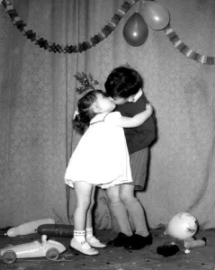 A little boy and girl kissing under the mistletoe at a Christmas party A little boy and girl kissing under the mistletoe at a Christmas party