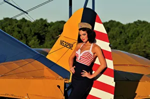 1940s style pin-up girl leaning on the tail fin of a Stearman biplane 1940s style pin-up girl leaning on the tail fin of a Stearman biplane