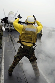 An aircraft director signals a F/A-18C Hornet on the flight deck of USS Kitty Hawk An aircraft director signals a F/A-18C Hornet on the flight deck of USS Kitty Hawk