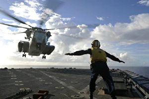 Aviation Boatswains Mate directs a CH-53E Super Stallion onto the flight deck of Aviation Boatswains Mate directs a CH-53E Super Stallion onto the flight deck of