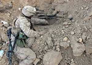 Iraq War Photos Prints: A combat engineer carefully scoops dirt away from a stack of mortar shells