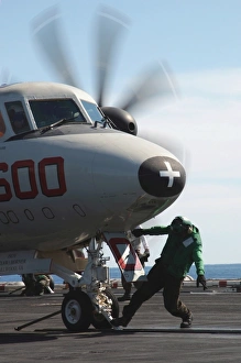 A flight deck crew member performs final checks on an E-2C Hawkeye A flight deck crew member performs final checks on an E-2C Hawkeye