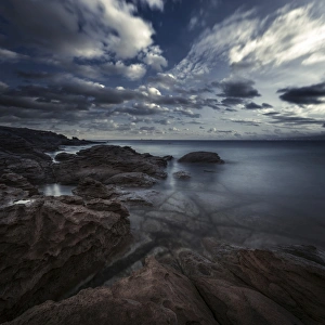 Huge rocks on the shore of a sea against a cloudy sky, Sardinia, Italy Huge rocks on the shore of a sea against a cloudy sky, Sardinia, Italy