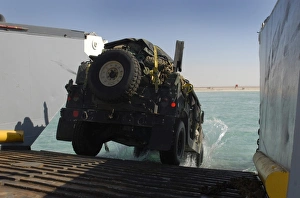 A Humvee drives down the ramp of a landing craft utility A Humvee drives down the ramp of a landing craft utility