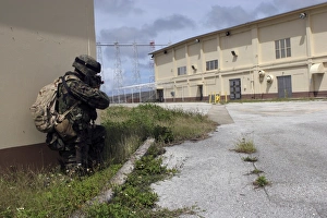 A Marine posts security as a team of Marines prepare to enter an enemy warehouse A Marine posts security as a team of Marines prepare to enter an enemy warehouse