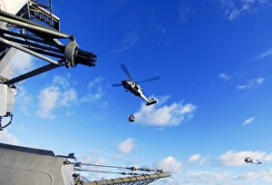 An MH-60S Sea Hawk helicopter transports cargo at sea An MH-60S Sea Hawk helicopter transports cargo at sea