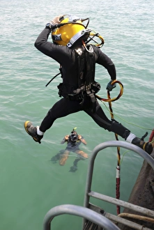 A photographer documents a Navy diver as he enters the water A photographer documents a Navy diver as he enters the water