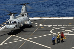 A plane captain signals to a CH-46E Sea Knight helicopter A plane captain signals to a CH-46E Sea Knight helicopter