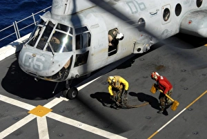 Sailors chock and chain a CH-46E Sea Knight helicopter Sailors chock and chain a CH-46E Sea Knight helicopter