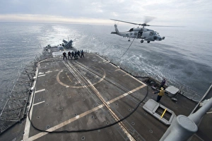 Sailors hold a fuel line during a helicopter-in-flight refueling exercise Sailors hold a fuel line during a helicopter-in-flight refueling exercise