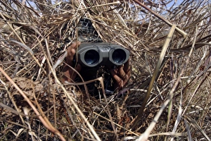 A scout observer practices observation techniques using a homemade ghillie suit A scout observer practices observation techniques using a homemade ghillie suit