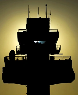 The setting sun silhouettes an air traffic control tower The setting sun silhouettes an air traffic control tower