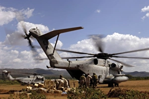 Soldiers and sailors help pile boxes of food and water off a CH-53E helicopter Soldiers and sailors help pile boxes of food and water off a CH-53E helicopter