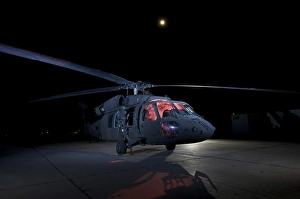 A UH-60 Black Hawk helicopter parked on the flight line under a full moon A UH-60 Black Hawk helicopter parked on the flight line under a full moon