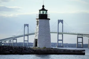 The Newport Harbor Light (Goat Island Light) standing framed by the giant Newport Bridge The Newport Harbor Light (Goat Island Light) standing framed by the giant Newport Bridge
