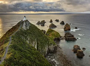 RF- Nugget Point (Ka Tokata) lighthouse at sunrise, rain clouds sweeping in from the horizon RF- Nugget Point (Ka Tokata) lighthouse at sunrise, rain clouds sweeping in from the horizon