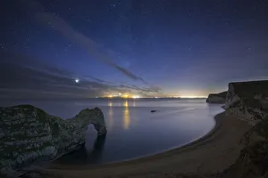 Stars and Milky Way over Durdle Door and the Jurassic Coast, with the lights of Weymouth Stars and Milky Way over Durdle Door and the Jurassic Coast, with the lights of Weymouth