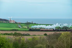 Steam train on the Heritage Poppy Line from Sheringham to Holt, with Weybourne Mill in background Steam train on the Heritage Poppy Line from Sheringham to Holt, with Weybourne Mill in background