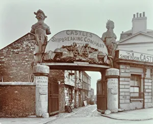 Prints of Ships figureheads over the gate at Castles Shipbreaking Yard, Baltic Wharf, Millbank, Westminster, London, March 1909. Entrance to the yard, with wooden figures salvaged from ships decorating the sign Greater London Prints: Ships Figureheads at Castles Yard, London, 1909 Print
