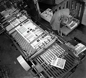 Finished brochures stacked near a print machine