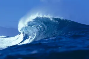 Side Angled View Of Big Blue Wave Curling With Spray, Blue Skies In Background Side Angled View Of Big Blue Wave Curling With Spray, Blue Skies In Background