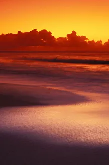 Beach At Sunset With Gentle Wave Rolling In, Dark Orange Sky With Silver Reflections Beach At Sunset With Gentle Wave Rolling In, Dark Orange Sky With Silver Reflections