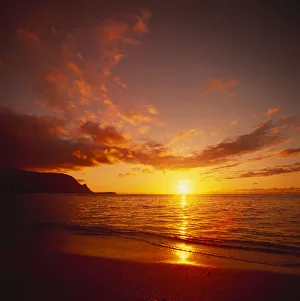 Calm Shoreline Ocean Waters With Orange Reflections From Sunset, Dark Orange Clouds Calm Shoreline Ocean Waters With Orange Reflections From Sunset, Dark Orange Clouds