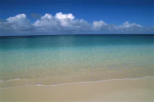 Calm Shoreline Water With Many Different Shades Of Blue, Clouds Above Horizon Calm Shoreline Water With Many Different Shades Of Blue, Clouds Above Horizon