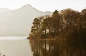 Calm Water With Mountains And Trees Along The Shoreline, England Calm Water With Mountains And Trees Along The Shoreline, England