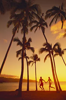 Couple Runs Together Holding Hands, Golden Sunset, Palm Trees, Ocean In Background Couple Runs Together Holding Hands, Golden Sunset, Palm Trees, Ocean In Background