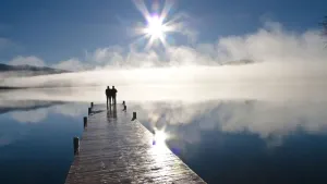 Couple Standing On A Dock And Silhouetted Against The Fog Lifting From Lake Whatcom During Winter Couple Standing On A Dock And Silhouetted Against The Fog Lifting From Lake Whatcom During Winter