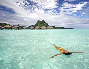 French Polynesia, Tahiti, Bora Bora, Woman Floating In Water Near Resort French Polynesia, Tahiti, Bora Bora, Woman Floating In Water Near Resort