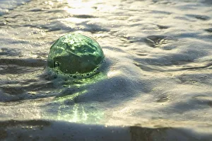 A Glass Fishing Ball Floats In Shallow Water, Bright Reflections A Glass Fishing Ball Floats In Shallow Water, Bright Reflections
