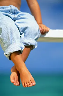 Hawaii, Legs And Feet Of Young Boy Sitting On A Bench By The Ocean Hawaii, Legs And Feet Of Young Boy Sitting On A Bench By The Ocean
