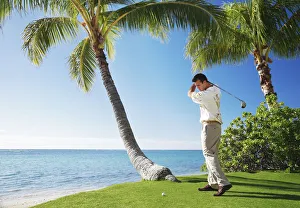 Hawaii, Oahu, Male Playing Golf, Ready To Swing His Golf Club At A Beach Front Golf Course Hawaii, Oahu, Male Playing Golf, Ready To Swing His Golf Club At A Beach Front Golf Course