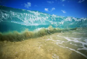 Hawaii, Turquoise Breaking Wave, Sand Visible Through Clear Water, Blue Sky. Close-Up Hawaii, Turquoise Breaking Wave, Sand Visible Through Clear Water, Blue Sky. Close-Up