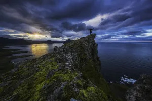 Man Standing On Top Of A Sea Cliff At Sunset Along Iceland's Strandir Coast In The West Fjord Region; Iceland Man Standing On Top Of A Sea Cliff At Sunset Along Iceland's Strandir Coast In The West Fjord Region; Iceland