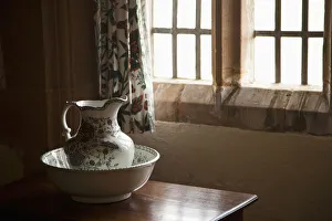 A Pitcher And Basin Sit On The Table Beside A Window; Lindisfarne, Northumberland, England A Pitcher And Basin Sit On The Table Beside A Window; Lindisfarne, Northumberland, England