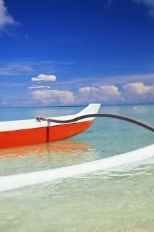 Red And White Outrigger Canoe Floating On Calm Turquoise Water Red And White Outrigger Canoe Floating On Calm Turquoise Water